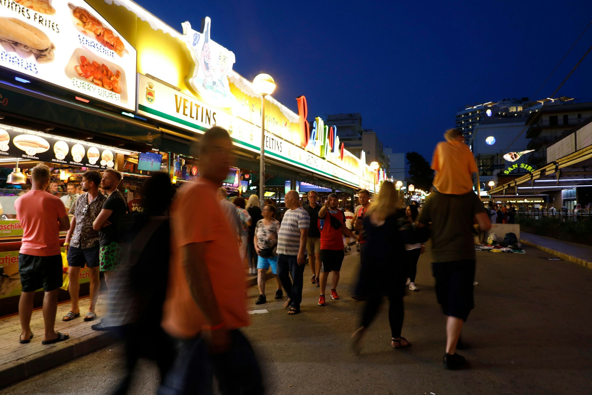 Menschen gehen an der Bar „Bamboleo“ in der Bierstraße am Ballermann vorbei. Der Sauftourismus um den Ballermann auf Mallorca ist nach Einschätzung von Unternehmern derzeit noch schlimmer als in den Jahren vor der Corona-Pandemie.