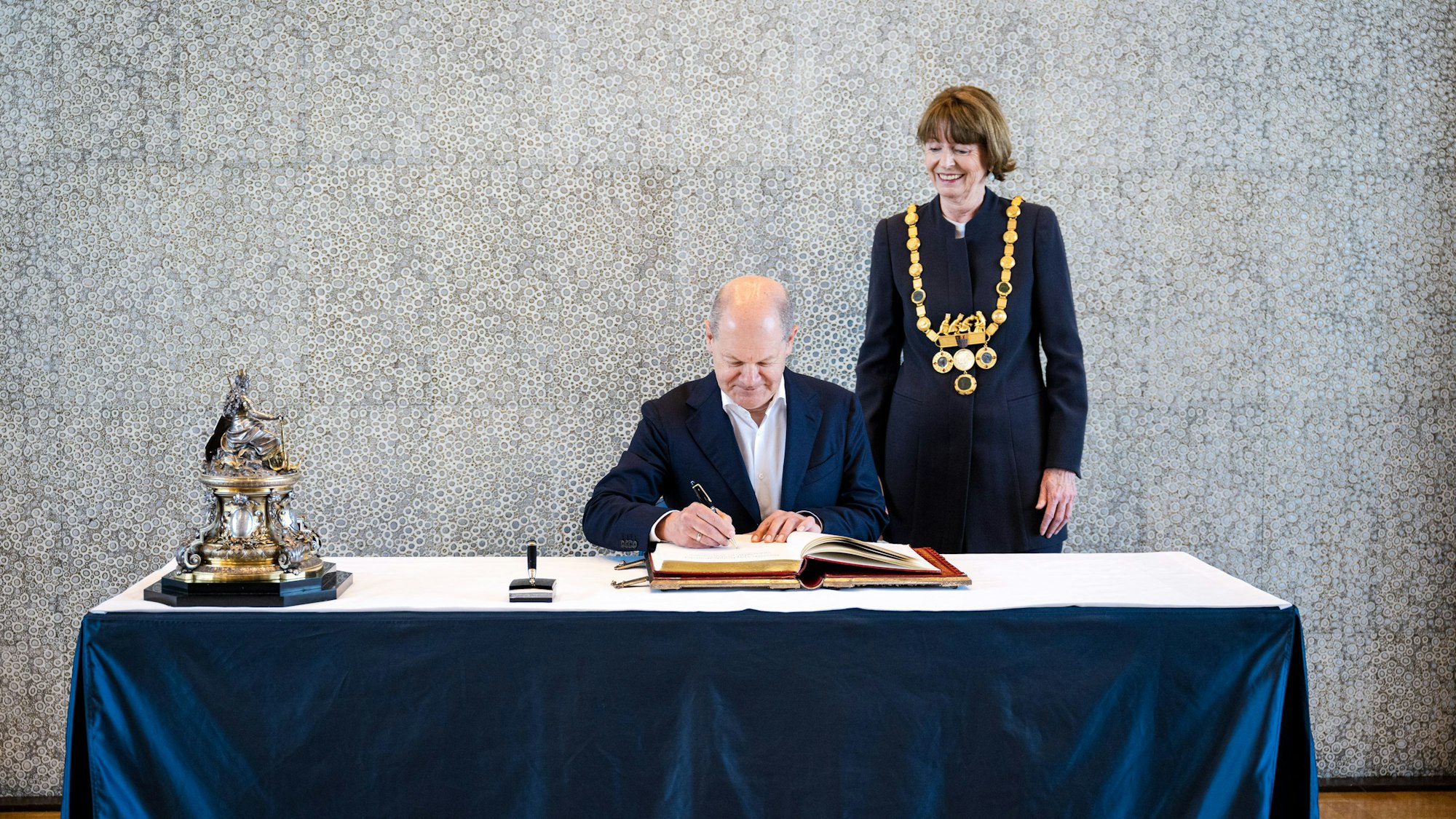 Im Beisein von OB Henriette Reker trägt sich Bundeskanzler Olaf Scholz in das Goldene Buch der Stadt Köln ein.