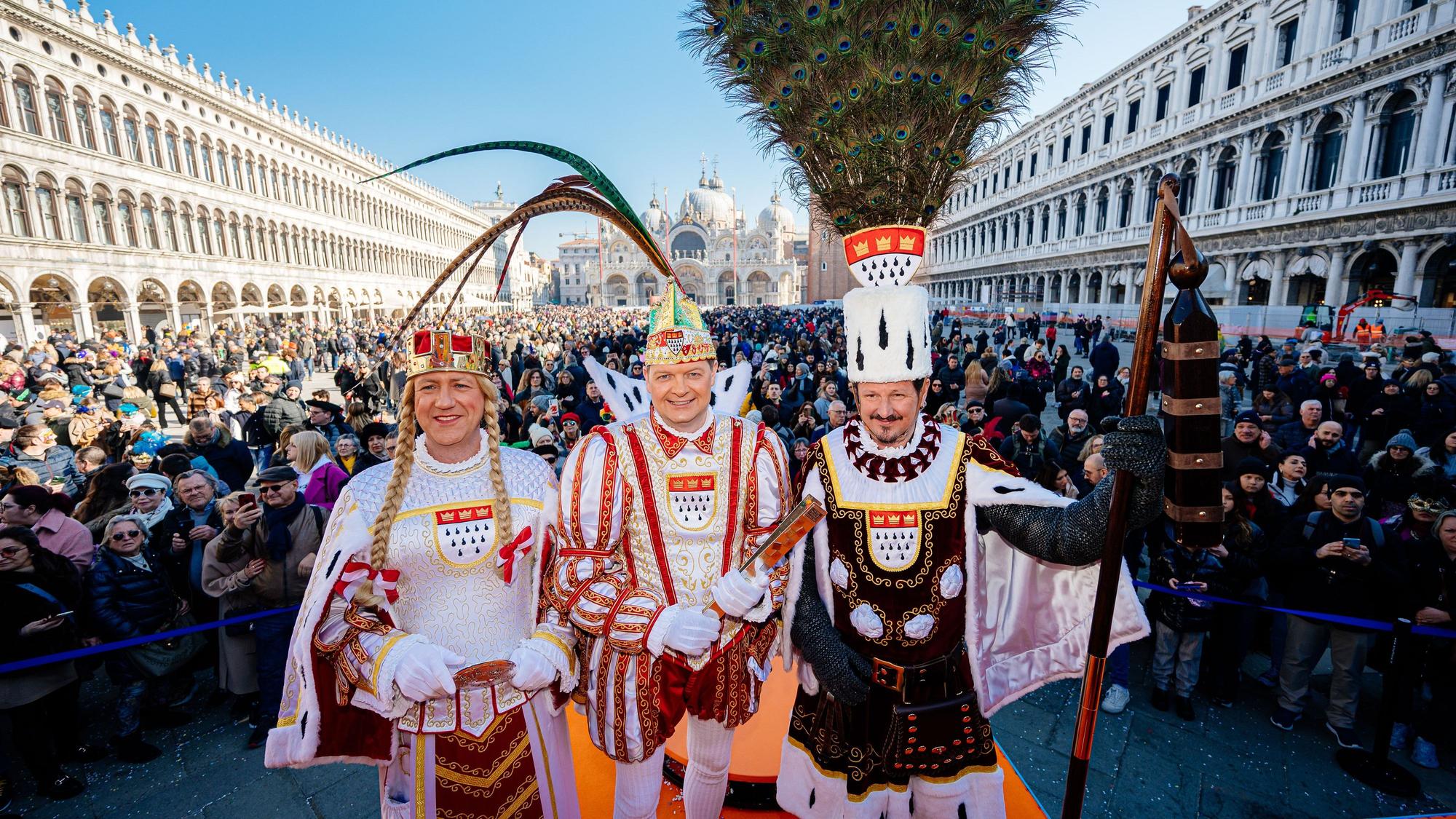 Das Kölner Dreigestirn steht mitten in Venedig und strahlt in die Kamera.
