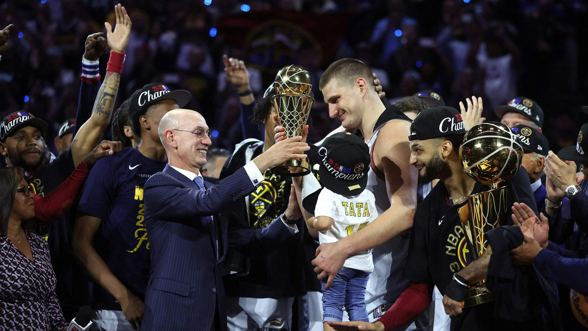 Nikola Jokic (Mitte) nimmt nach dem NBA-Titel mit den Denver Nuggets die Trophäe für den Finals-MVP entgegen.