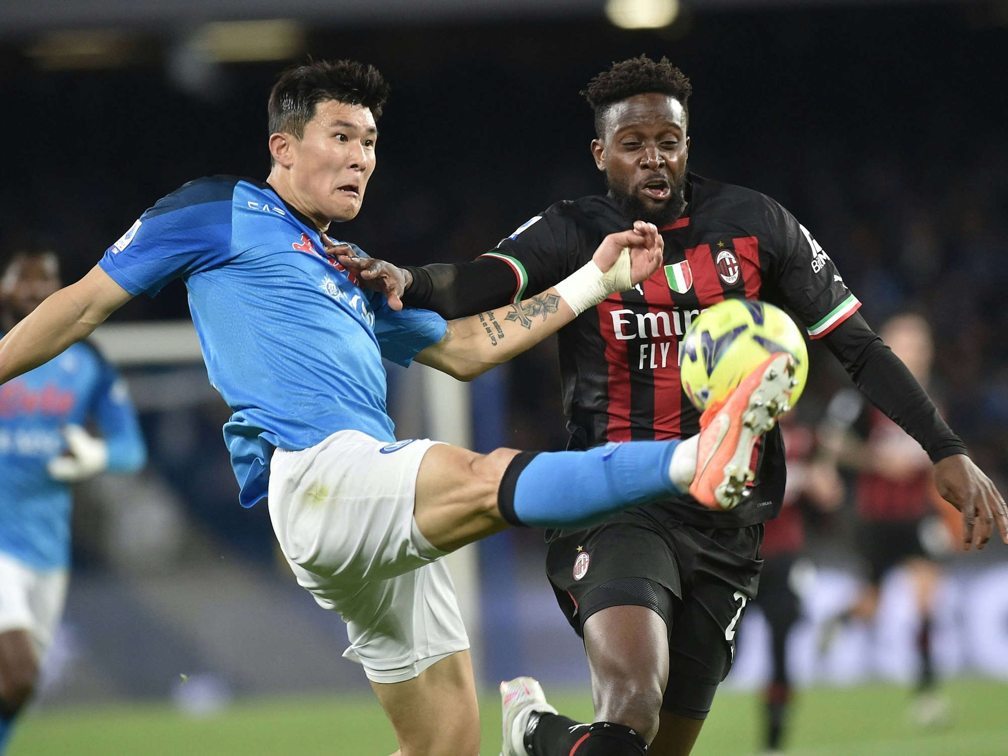 Min-Jae Kim (l.) von der SSC Neapel reißt sein Bein hoch, um an den Ball zu kommen. Pierre Kalulu von der AC Mailand kommt nicht rechtzeitig an den Ball.