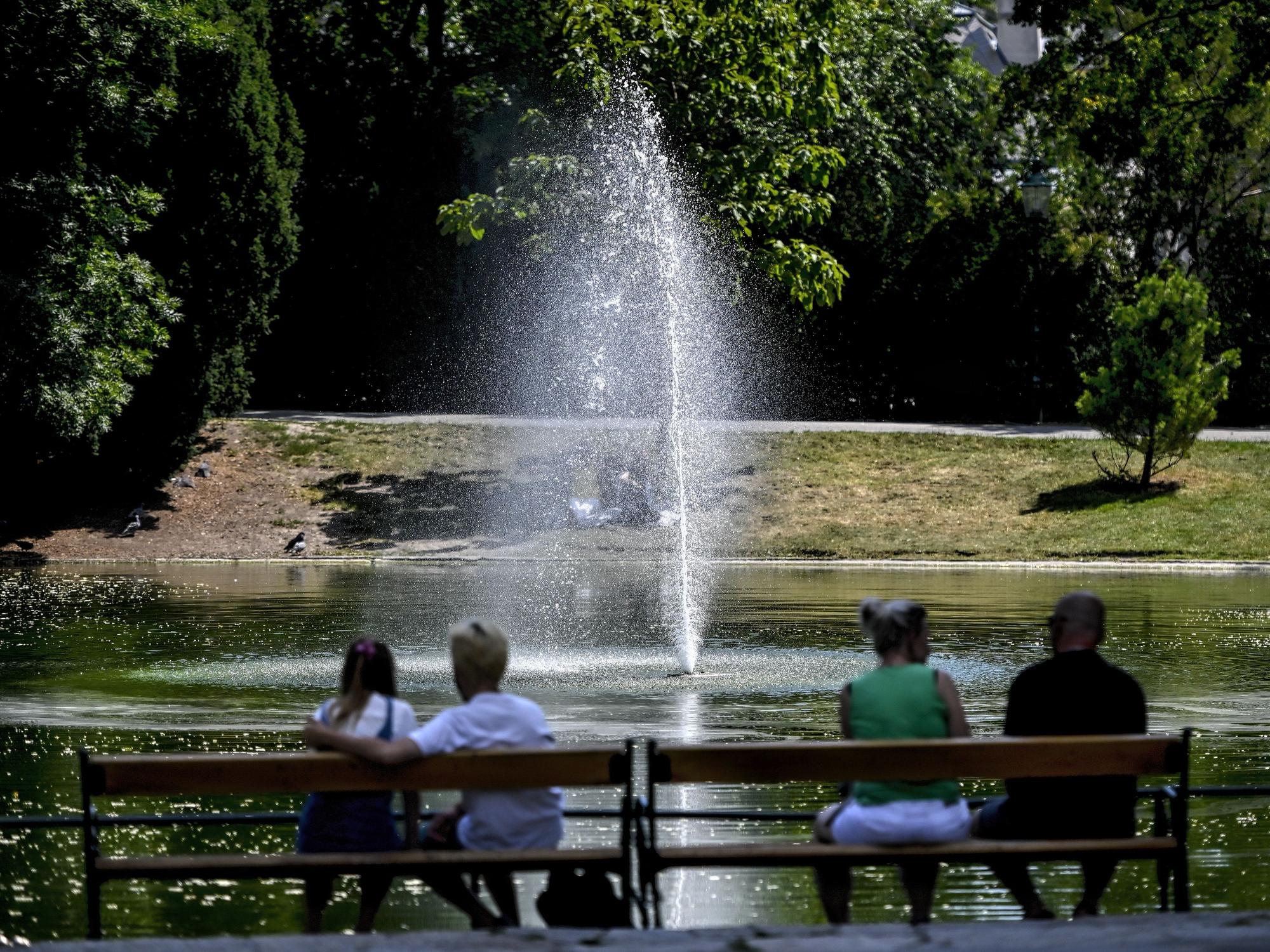Menschen sitzen im Schatten auf einer Parkbank im Wiener Stadtpark