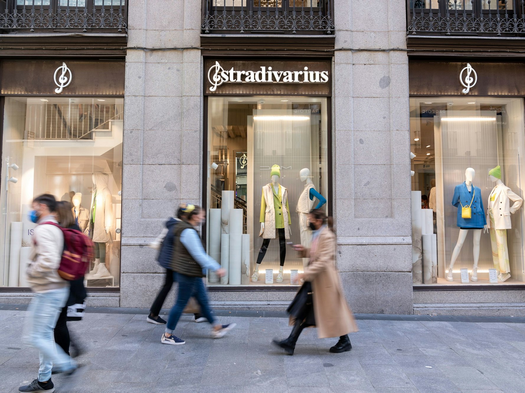 Menschen gehen an einem Schaufenster eines Stradivarius-Geschäfts vorbei, das zur Inditex-Gruppe gehört, hier im März 2022 in Madrid.