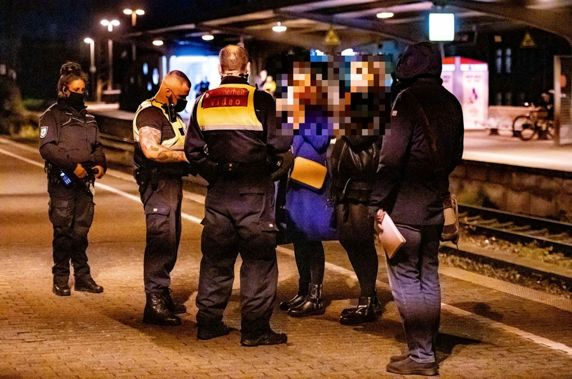 Polizei und Bahn-Mitarbeiter kontrollieren am Bahnhof Köln-Süd zwei Personen.