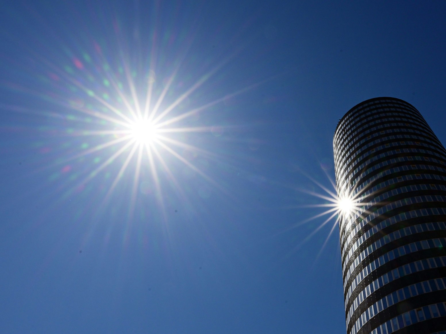 Die Sonne scheint vom wolkenlosen Himmel und spiegelt sich im Glas des JenTower.
