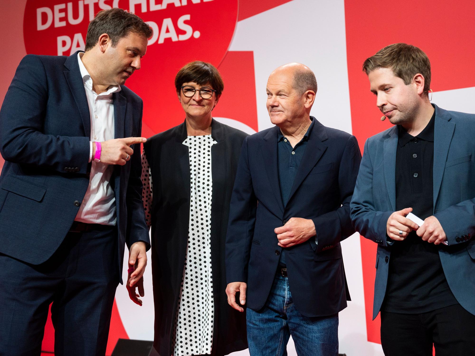 Lars Klingbeil, Saskia Esken, Bundeskanzler Olaf Scholz und Kevin Kühnert stehen auf einer Bühne.