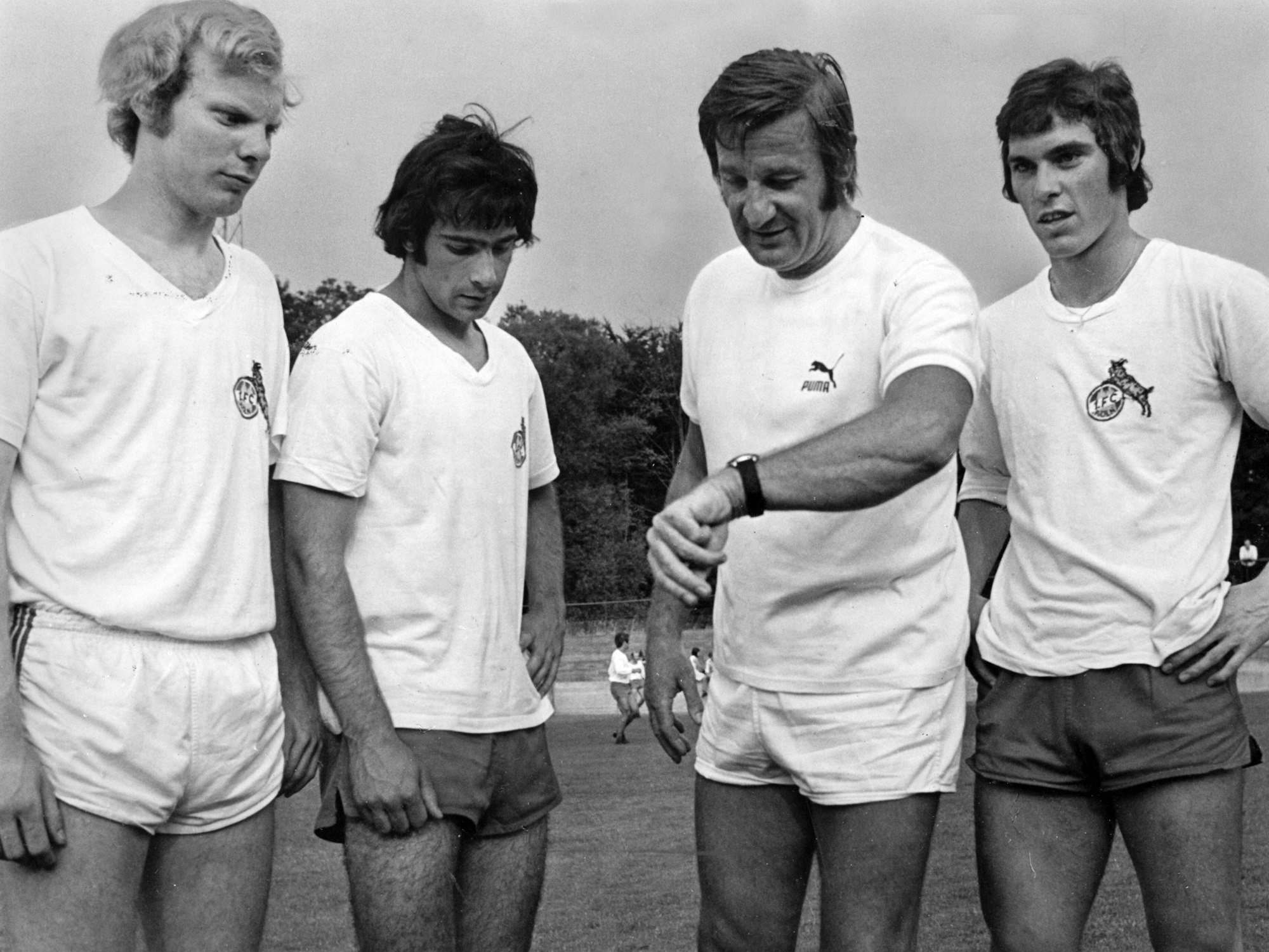 Josef Bläser (v.l.n.r.), Harald Konopka, Trainer Gyula Lorant und Jürgen Glowacz stehen beim Training auf dem Platz.