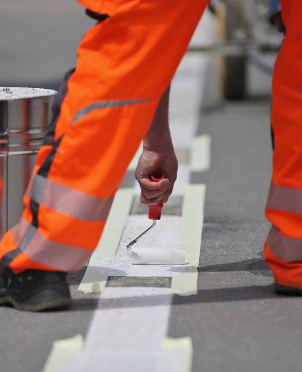 Ein Arbeiter vervollständigt eine Straßenmarkierung