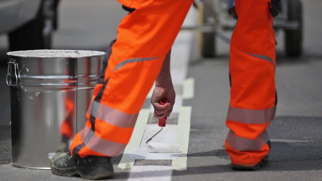Ein Arbeiter vervollständigt eine Straßenmarkierung