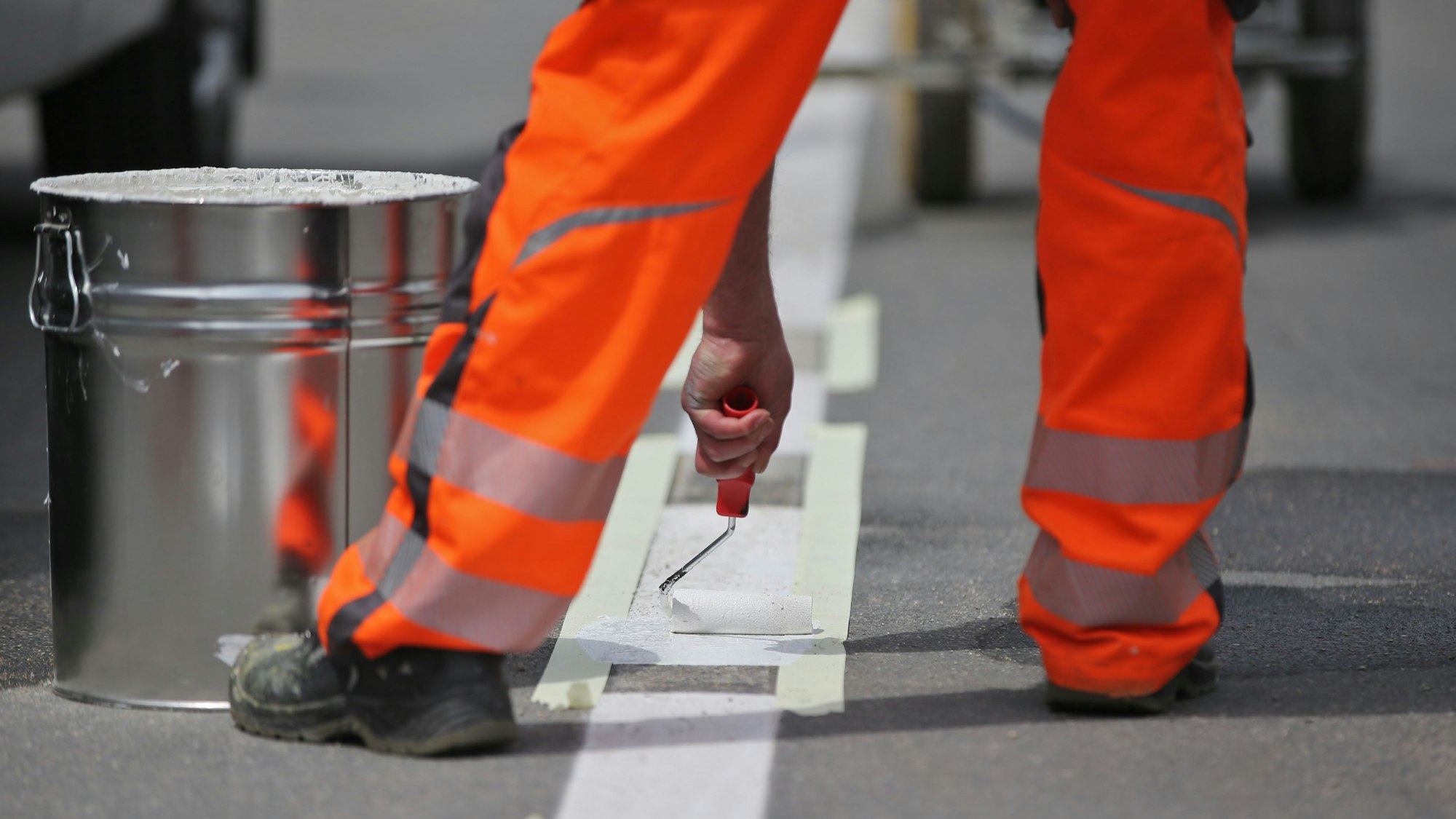 Ein Arbeiter vervollständigt eine Straßenmarkierung