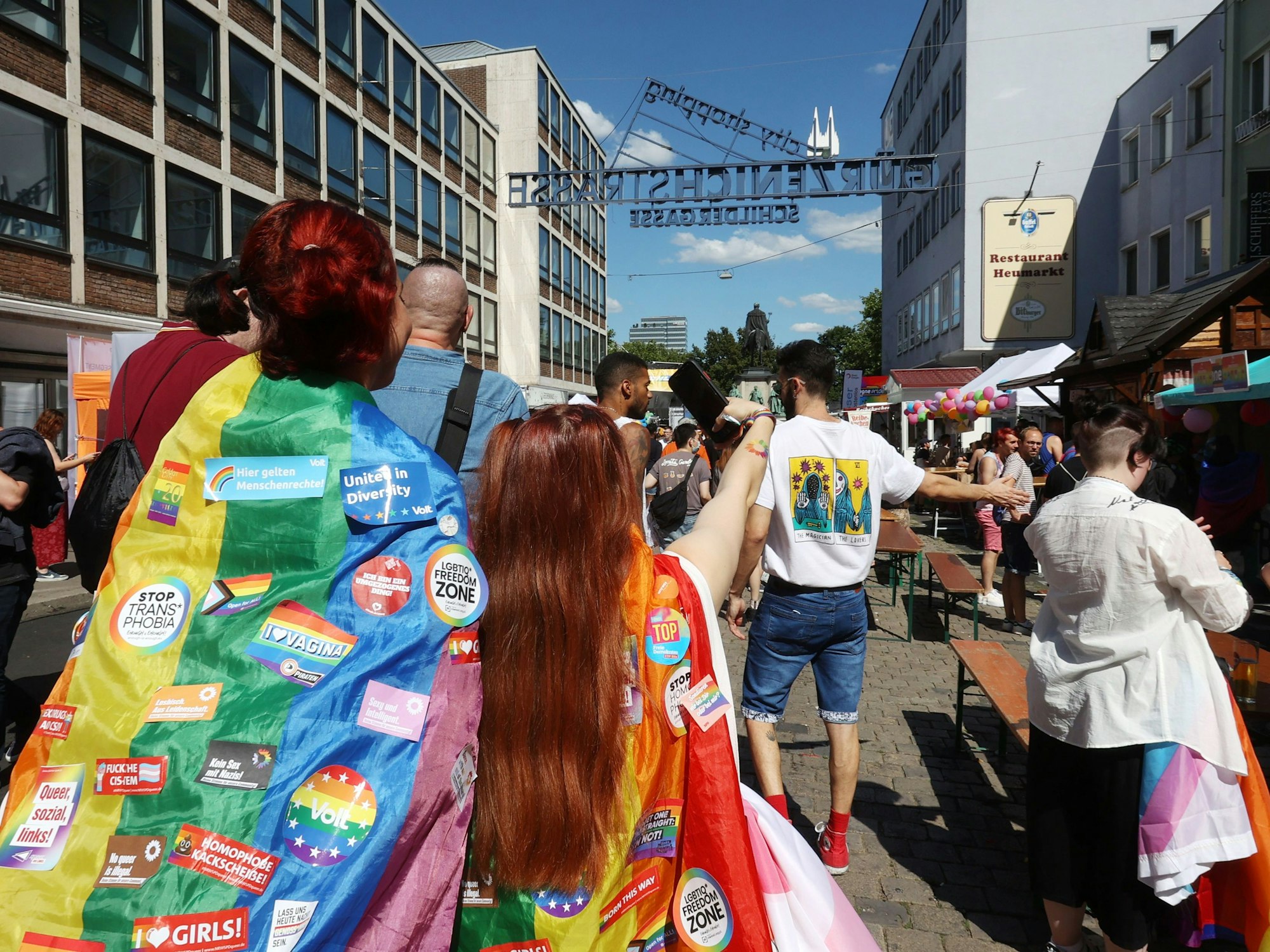 Menschen tragen Regenbogenflaggen und laufen bei der CSD-Demonstration in Köln mit.