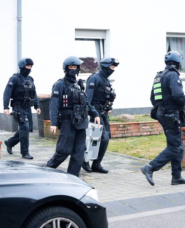 Einsatzkräfte der Polizei bei einer Razzia in einer Einfahrt in Köln.