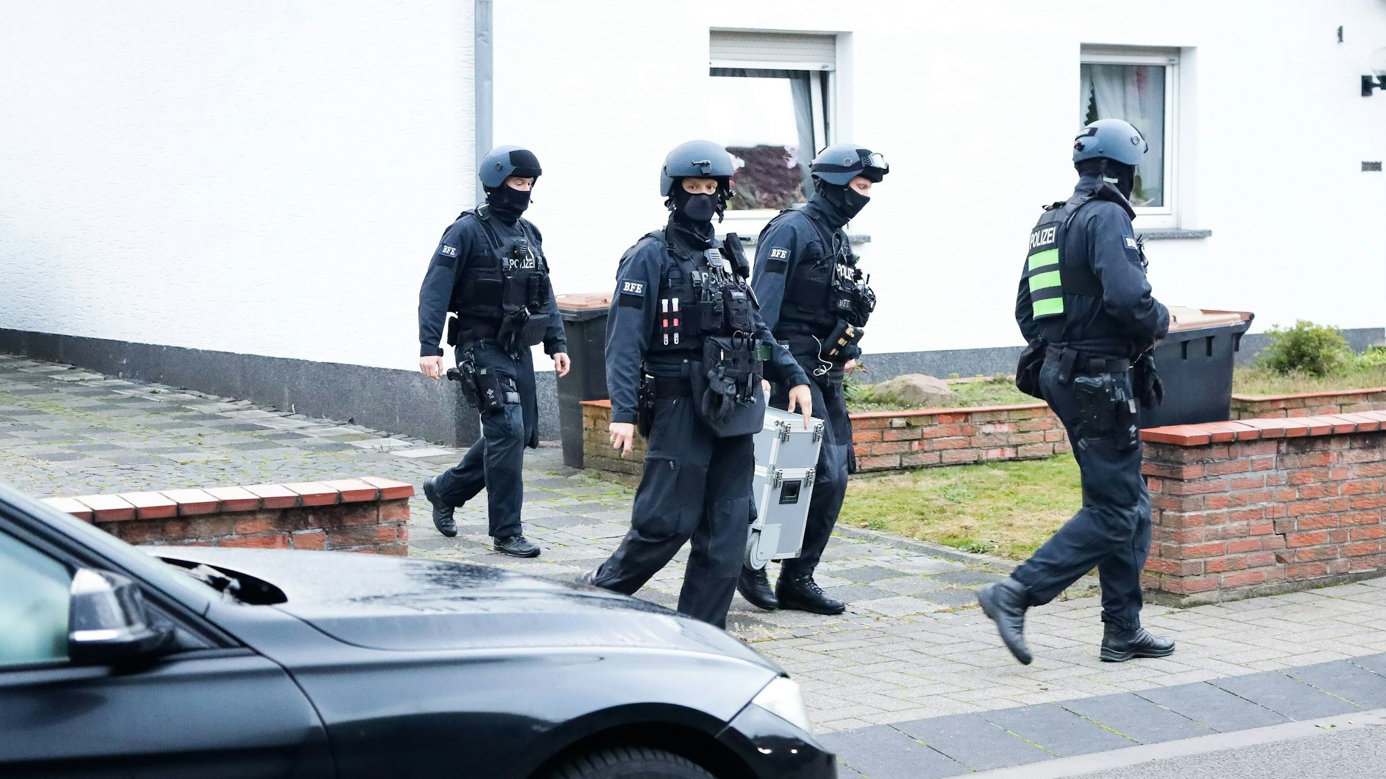 Einsatzkräfte der Polizei bei einer Razzia in einer Einfahrt in Köln.