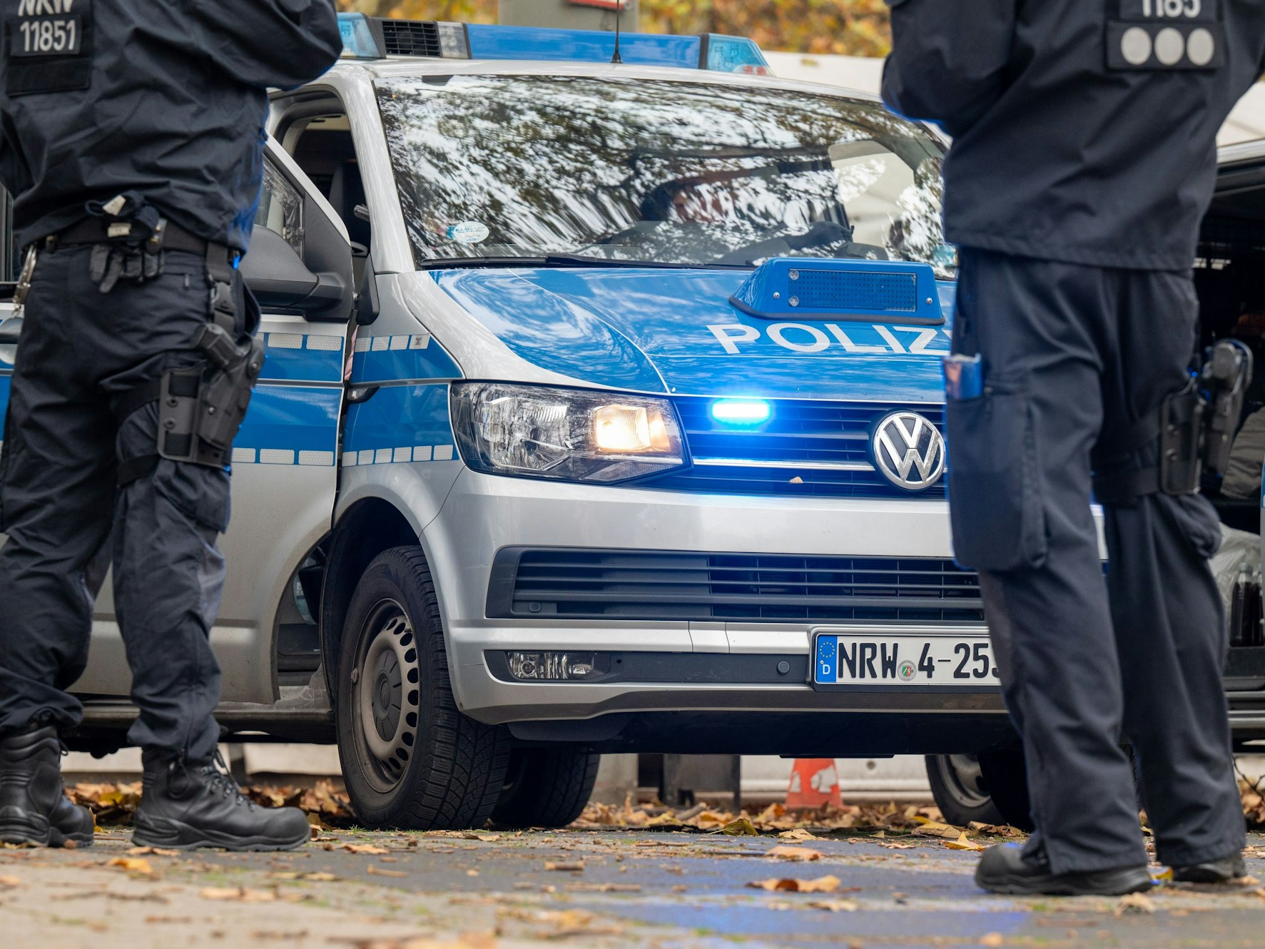 Polizisten stehen um ein Polizeifahrzeug herum.