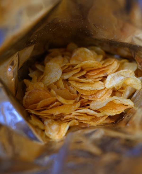Eine offene Tüte Kartoffelchips liegt auf einem Tisch.