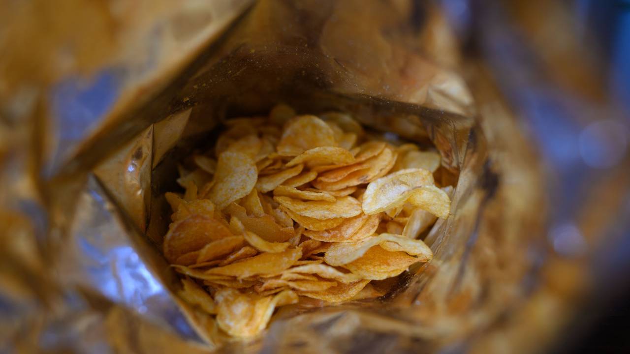 Eine offene Tüte Kartoffelchips liegt auf einem Tisch.