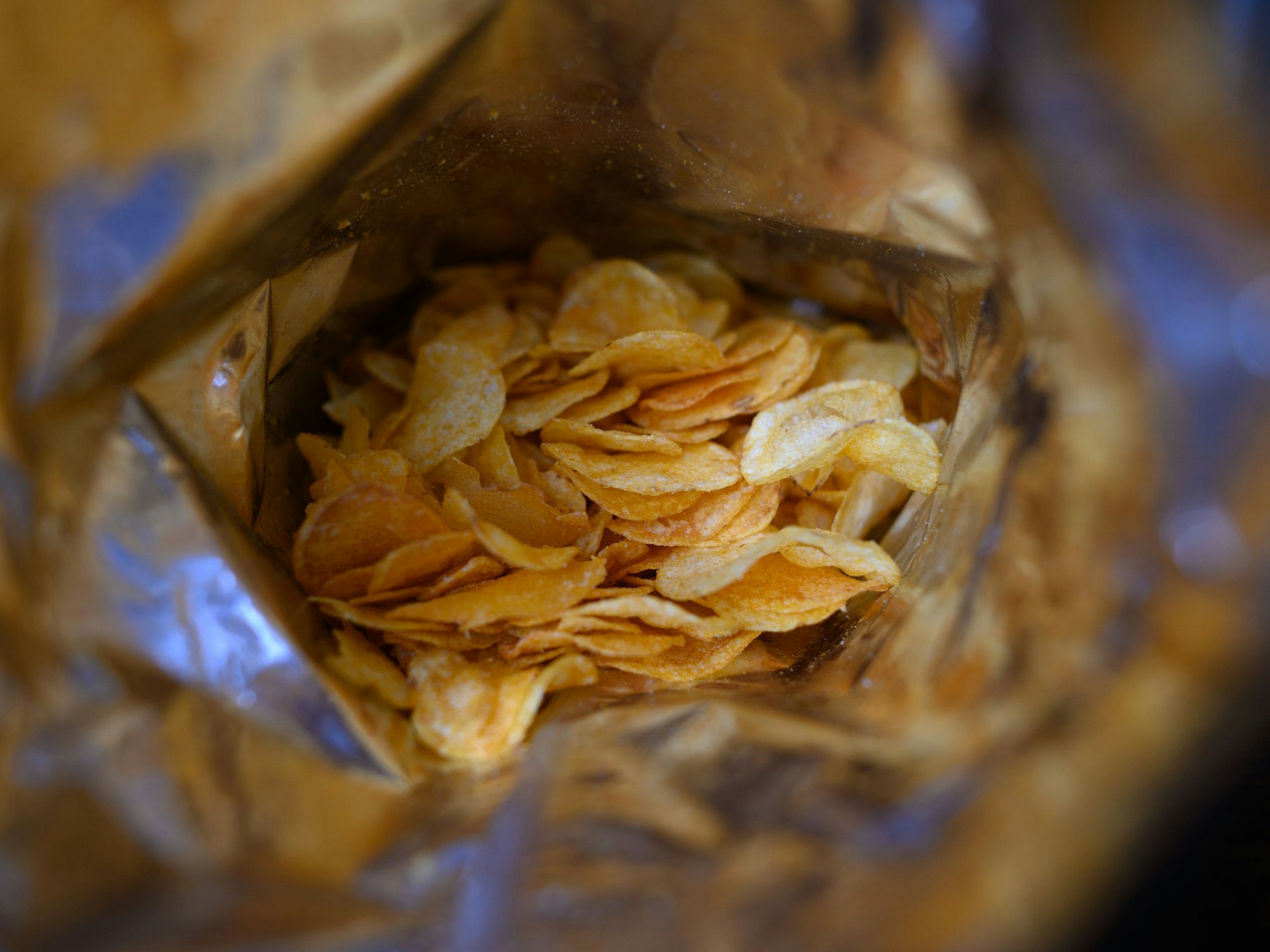 Eine offene Tüte Kartoffelchips liegt auf einem Tisch.