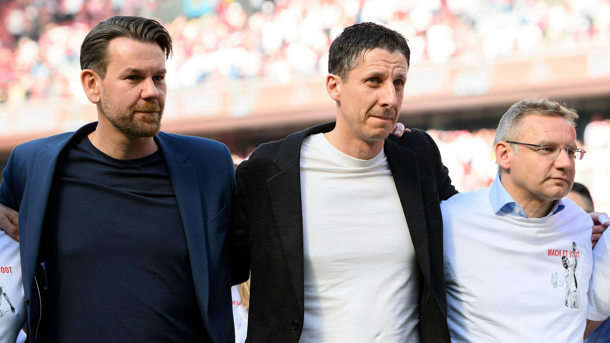 Thomas Kessler, Christian Keller und Eckhard Sauren stehen Arm in Arm im Rhein-Energie-Stadion.