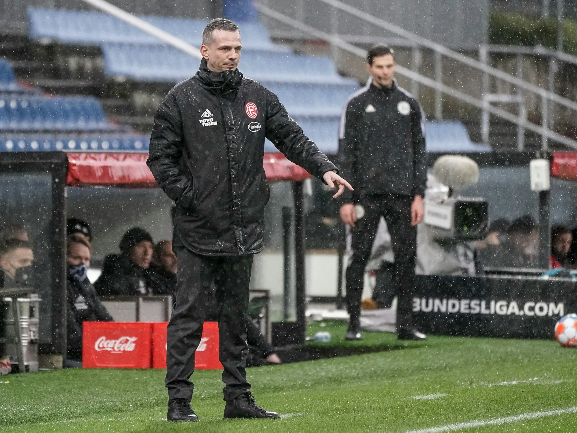 Fortuna Düsseldorfs Trainer Christian Preußer steht im Regen an der Seitenlinie beim Spiel bei Holstein Kiel.