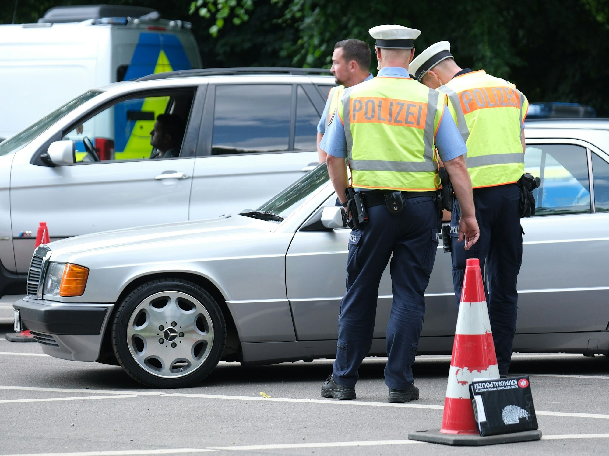 Zwei Polizeibeamte kontrollieren einen Pkw.
