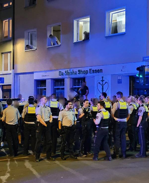 Polizisten bewachen Mitglieder einer anderen der beteiligten Gruppen einer Schlägerei in der Essener Innenstadt.