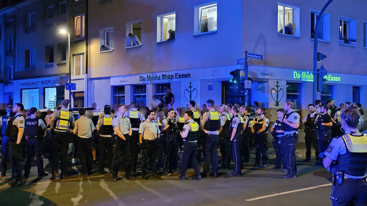 Polizisten bewachen Mitglieder einer anderen der beteiligten Gruppen einer Schlägerei in der Essener Innenstadt.