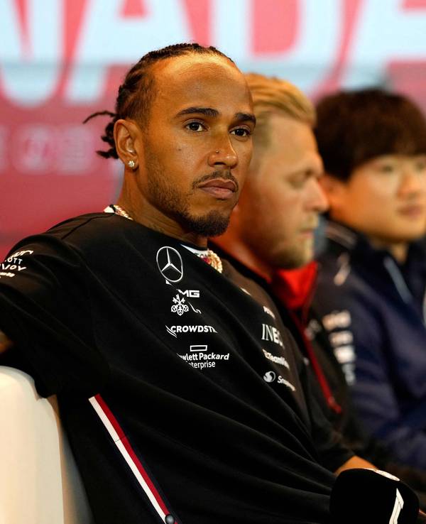 Lewis Hamilton sitzt entspannt auf einem Sofa.