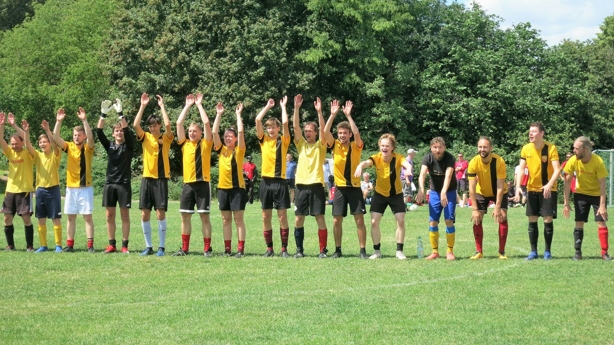 Die Kölner Mannschaft „Betong Union“ steht jubelnd auf einer Wiese.