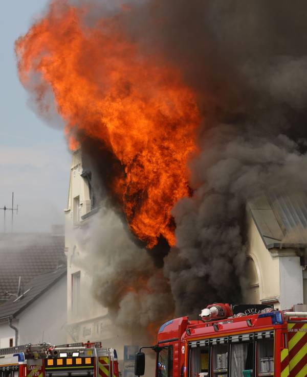 Flammen schlagen aus einem Dach. Ein Motorradladen ist in Sankt Augustin im Rhein-Sieg-Kreis in Brand geraten.