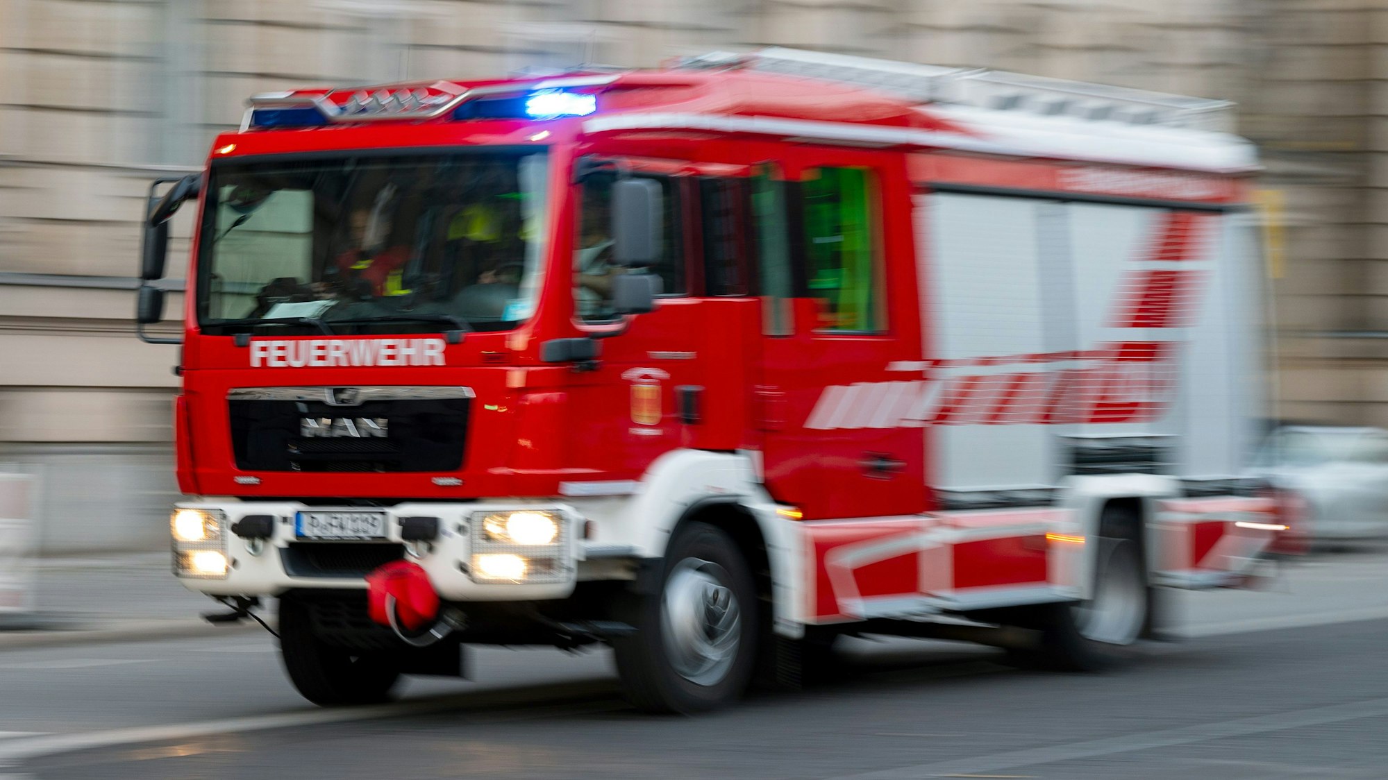 Ein Feuerwehrauto mit eingeschaltetem Blaulicht fährt zum Einsatz.