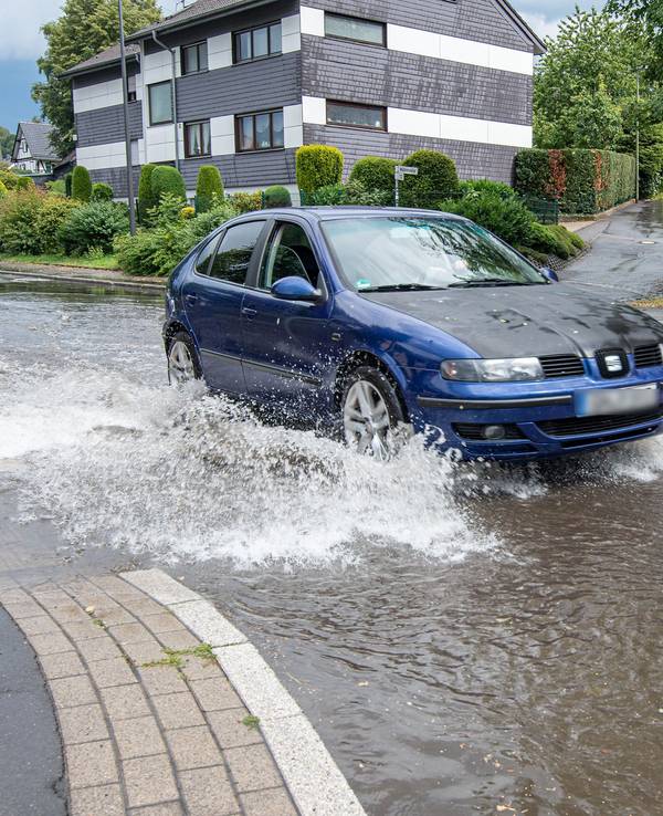 Ein Auto fährt nach Starkregen durch eine überflutete Straße. +++ dpa-Bildfunk +++