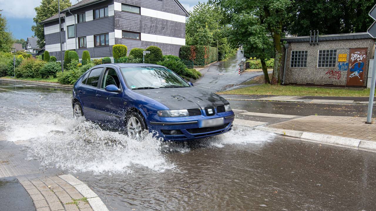 Ein Auto fährt nach Starkregen durch eine überflutete Straße. +++ dpa-Bildfunk +++