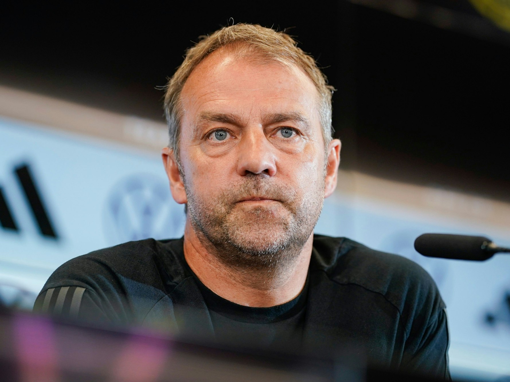 Bundestrainer Hansi Flick sitzt auf dem Podium.