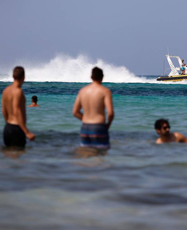 Eine Schlauchboot mit Touristen fährt neben den Badegästen am Strand von El Arenal in Palma de Mallorca, einem der Hauptziele für deutsche und niederländische Touristen während der Sommersaison.