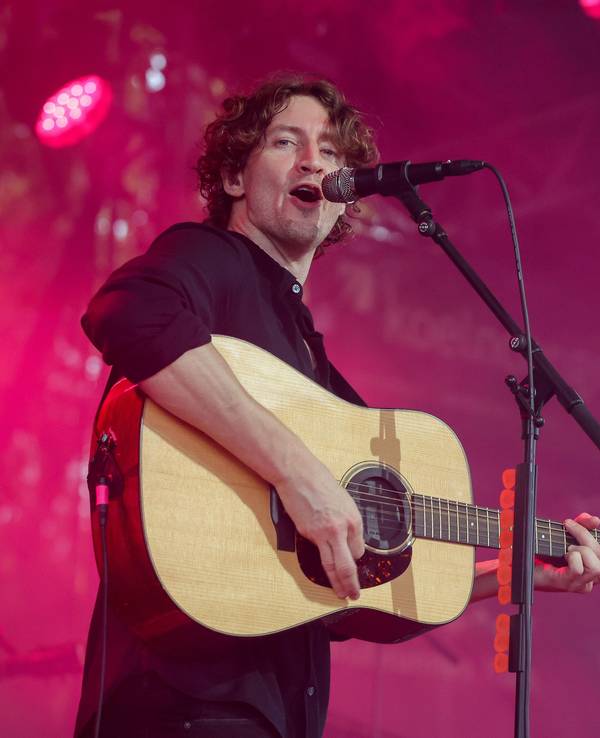 Dean Lewis steht mit seiner Gitarre auf der Bühne und singt.