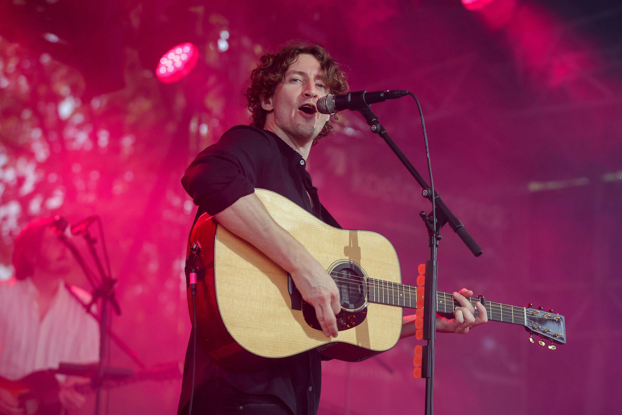 Dean Lewis steht mit seiner Gitarre auf der Bühne und singt.