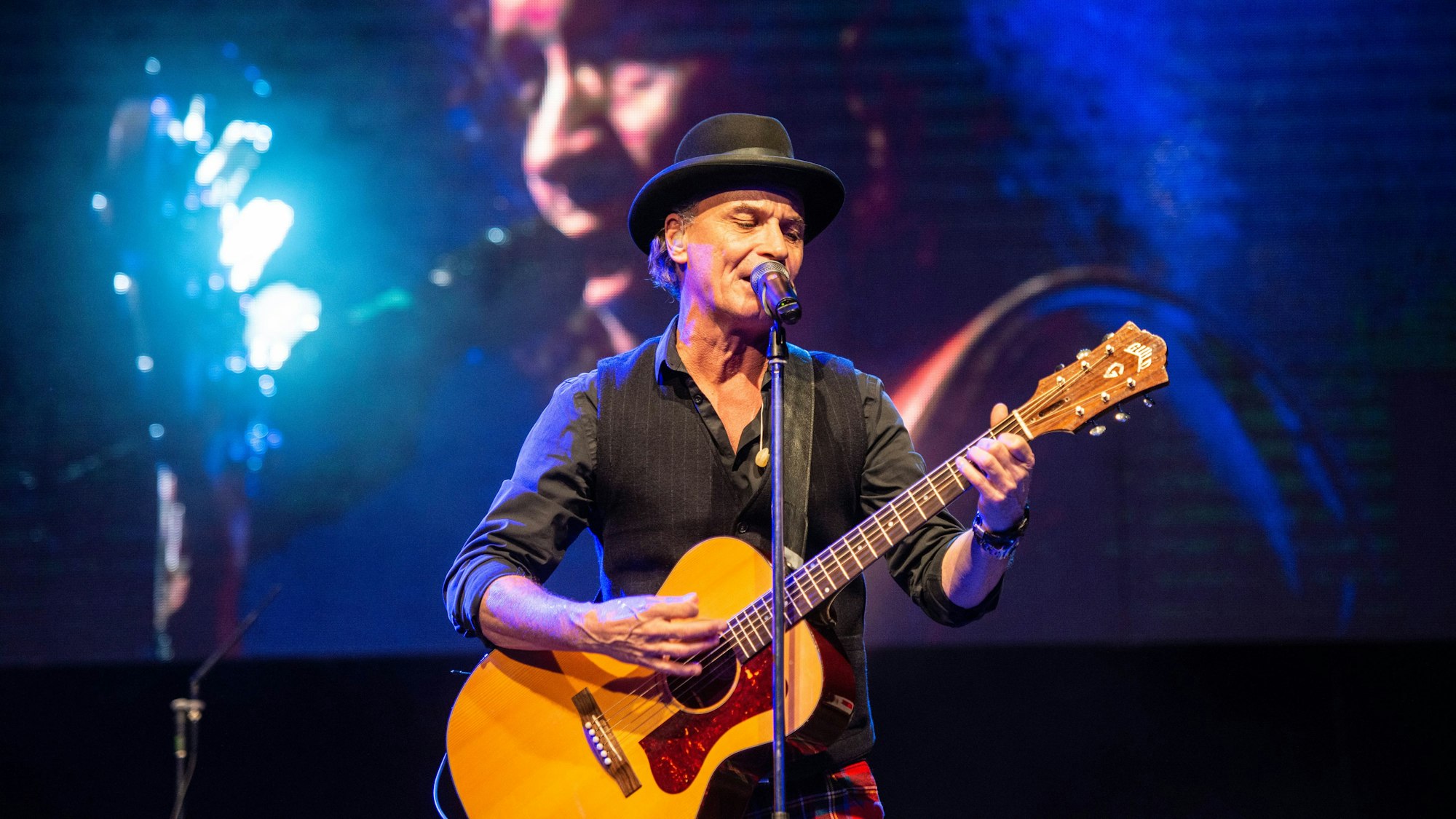 Peter Brings steht mit Gitarre auf der Bühne im Kölner Tanzbrunnen und singt.