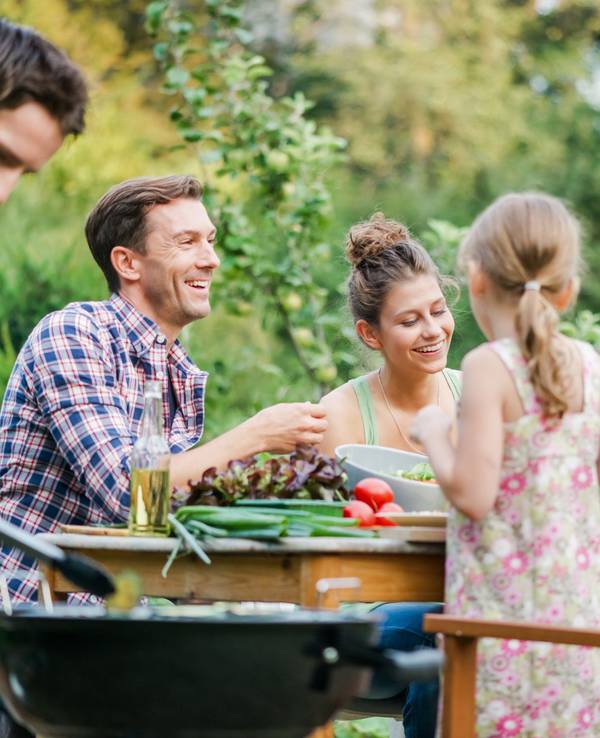 Familie sitzt im Garten beim Essen