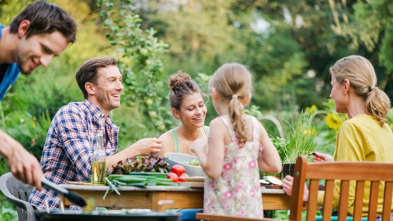 Familie sitzt im Garten beim Essen
