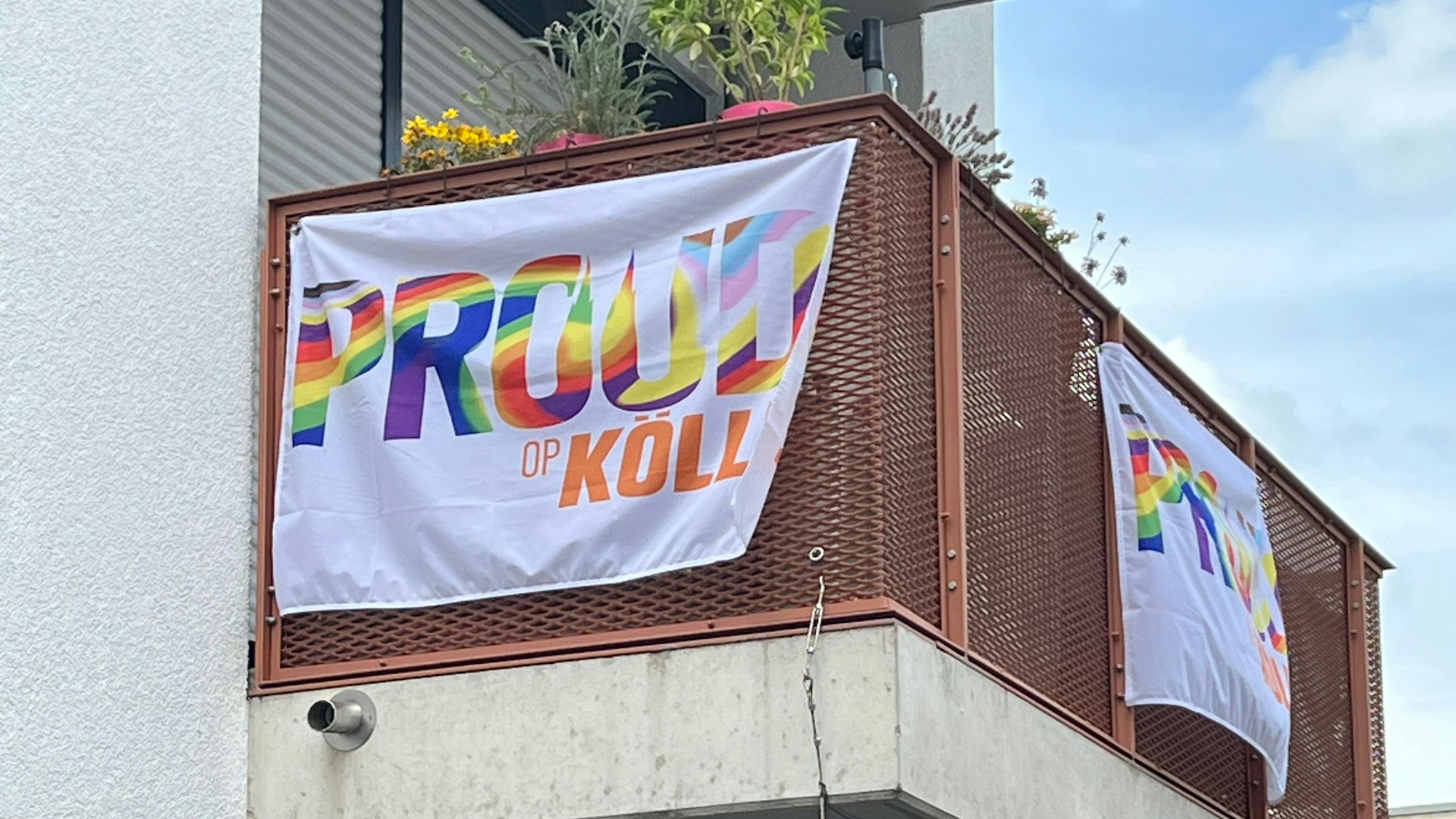 Fahnen mit der Aufschrift „Proud op Kölle“ hängen an einem Balkon in Köln-Nippes.