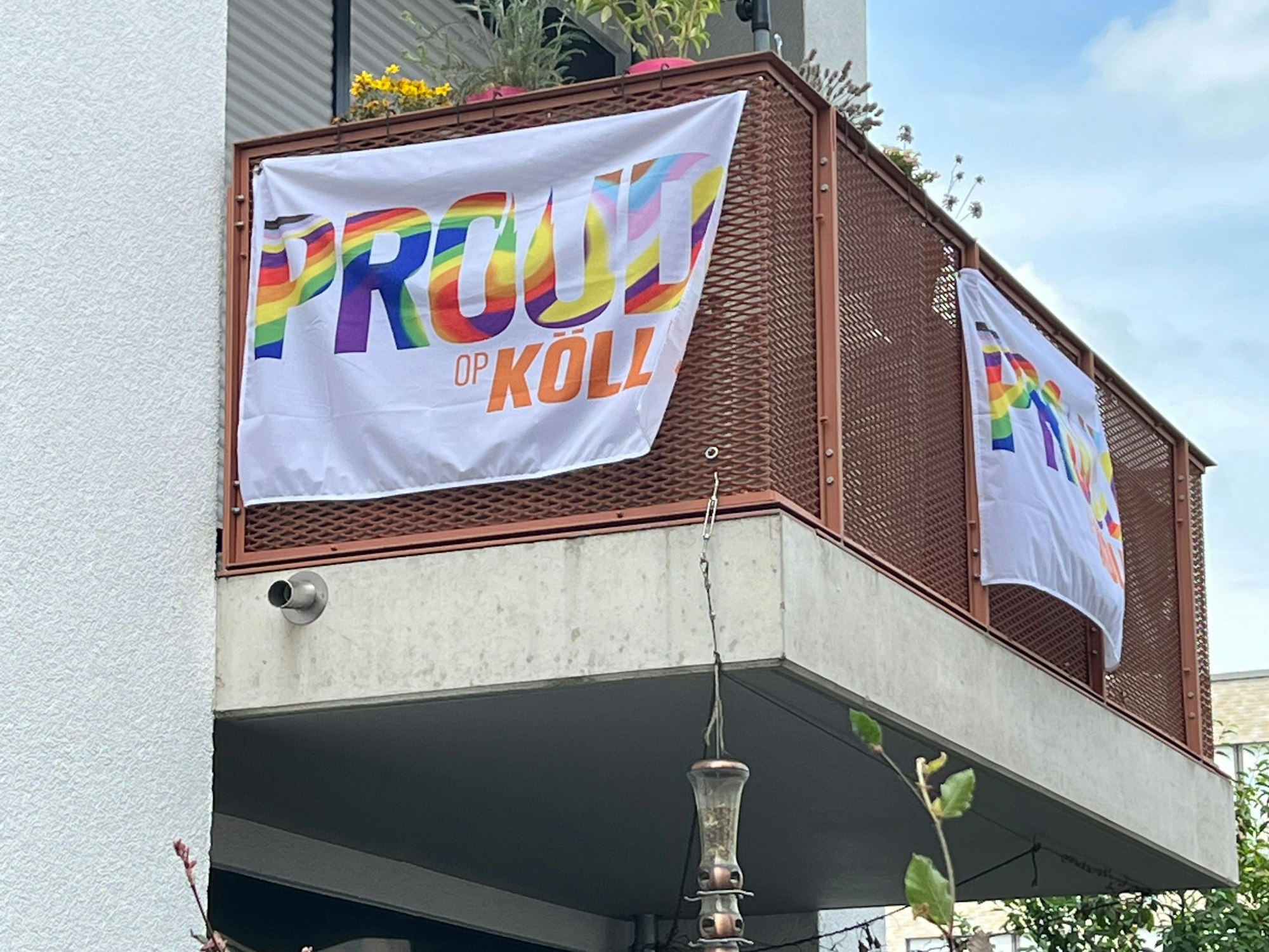 Fahnen mit der Aufschrift „Proud op Kölle“ hängen an einem Balkon in Köln-Nippes.