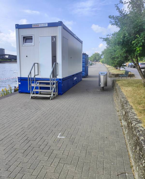 Ein Klo-Container steht am Rhein.
