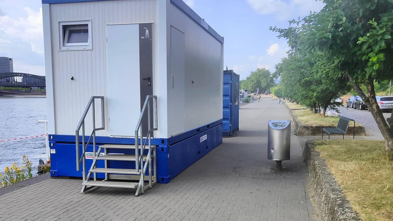 Ein Klo-Container steht am Rhein.