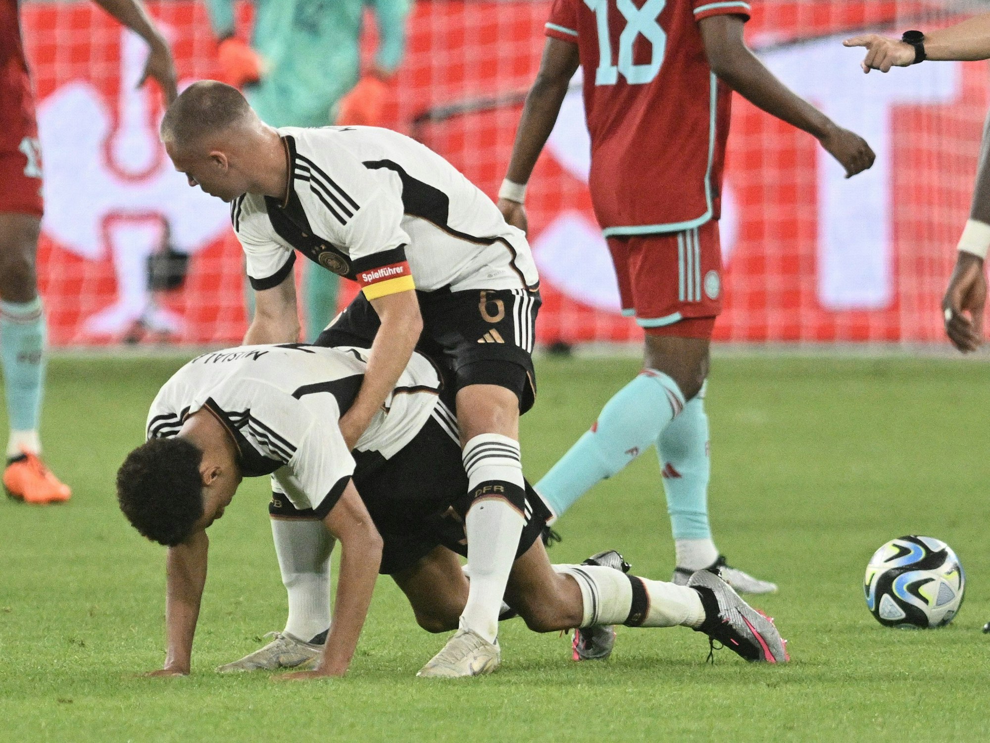 Deutschlands Joshua Kimmich (oben) hilft Jamal Musiala beim Aufstehen.