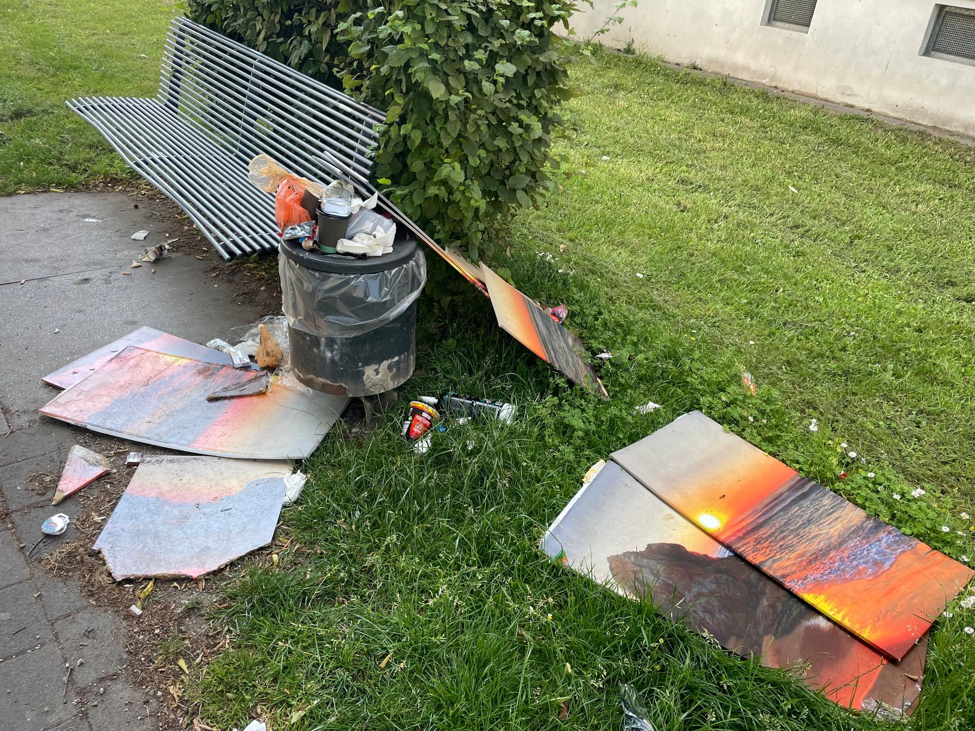 Eine Parkbank umgeben von Müll in einer Wohnsiedlung in Vingst.