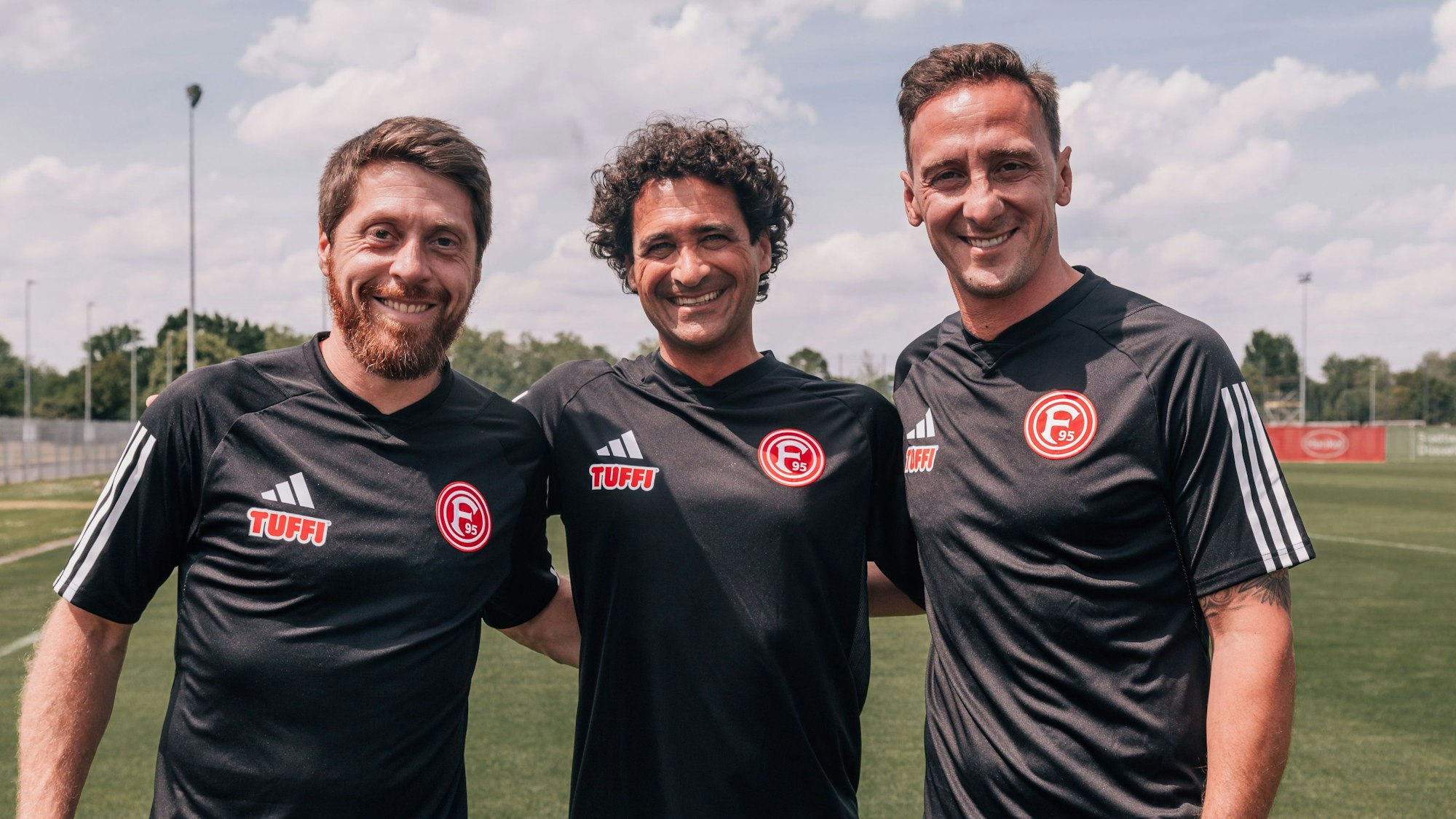 Assistent Andreas „Lumpi“ Lambertz, Düsseldorfs U23-Cheftrainer Nicolas Michaty und der neue Co-Trainer Ahmet Cebe posieren gemeinsam auf dem Platz.