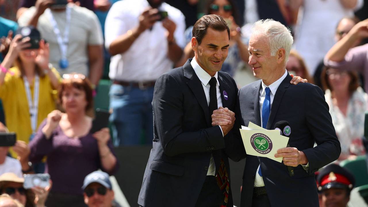 Die beiden ehemaligen Tennisstars Roger Federer (l.) und John McEnroe (r.) geben sich im Rahmen des Tennisturniers vom Wimbledon die Hand.