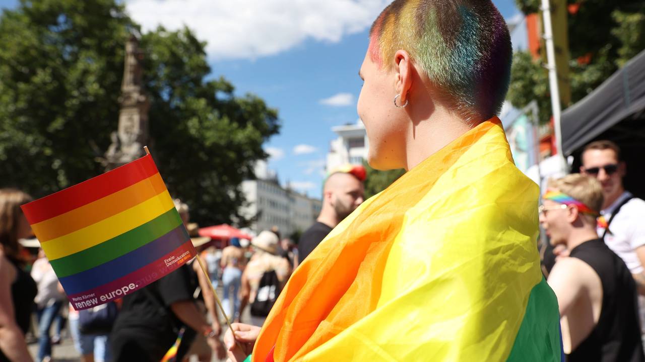 Eine junge Frau, die auf der CSD-Demo 2022 eine Regenbogenfahne trägt.