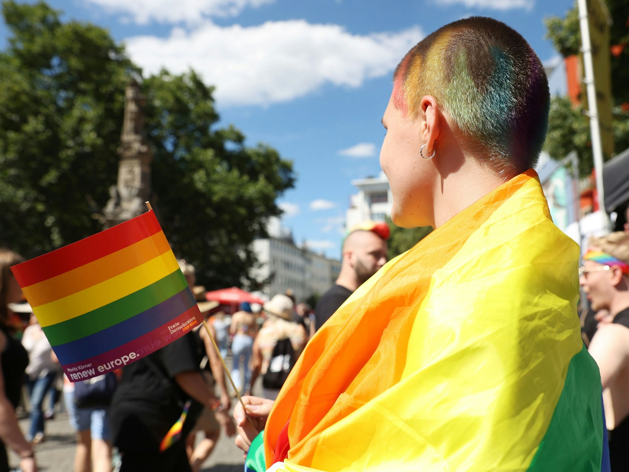Eine junge Frau, die auf der CSD-Demo 2022 eine Regenbogenfahne trägt.