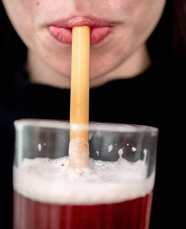Junge Frau trinkt durch einen Strohhalm.